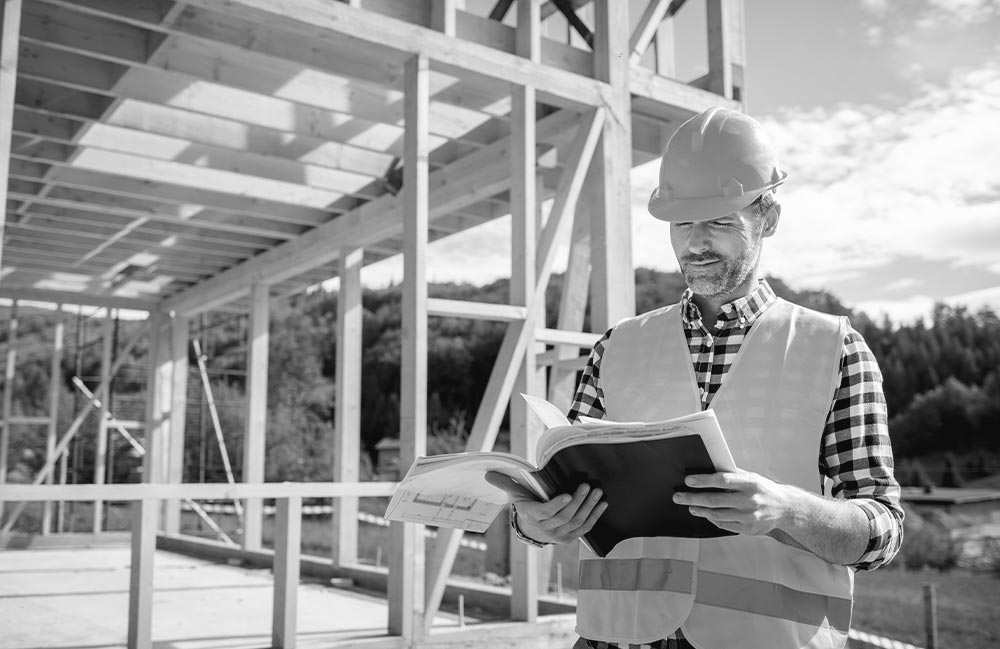 engineer-with-hardhat-and-blueprints-on-building